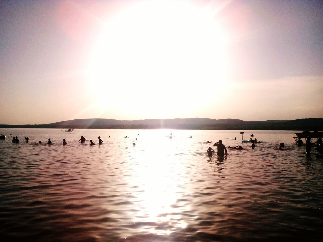 SILHOUETTE PEOPLE SWIMMING IN SEA AGAINST SKY DURING SUNSET