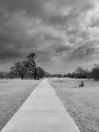 Bare trees on field against sky during winter