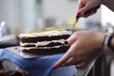 Cropped image of woman hand icing cake in kitchen
