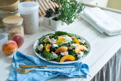 Top view plate with tasty peach and spinach salad on wooden table with copy space