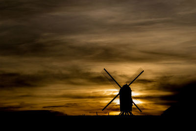 Low angle view of traditional windmill against cloudy sky