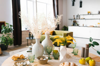 Festive easter table with mimosa flowers in a vase and traditional food, eggs