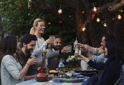 Multi-ethnic friends toasting drinks at dinner table in yard