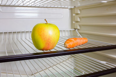 Apple and carrot on shelf in refrigerator