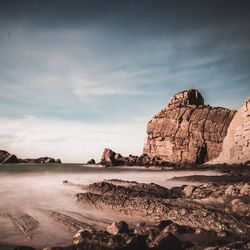 Rock formations by sea against sky