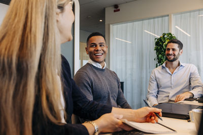 Smiling male and female business colleagues discussing in coworking office