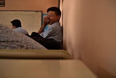 Happy boy covering mouth while sitting on bench in school