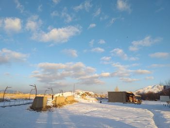 Buildings on snow covered field against sky