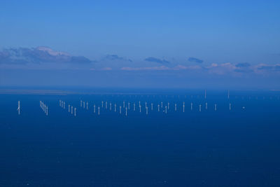 Windmills in sea against sky