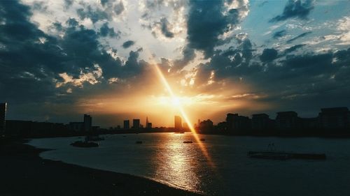 Sunset over river with buildings in background