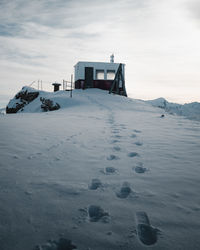 House on snow covered land against sky