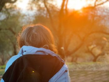 Rear view of woman with umbrella against orange trees