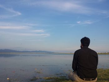 Rear view of man looking at sea against sky