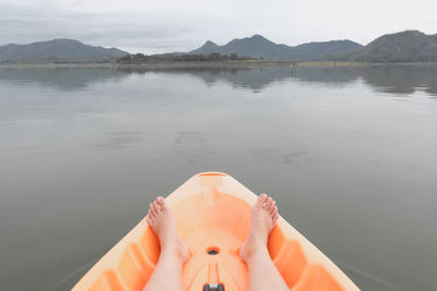 Low section of person on lake against mountain