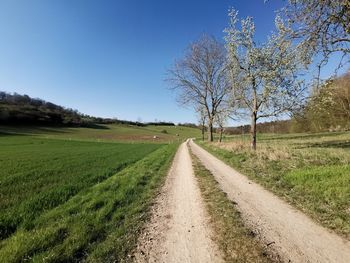 Road amidst field against clear sky