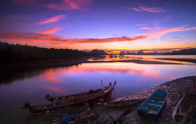 Boats moored in lake against sky during sunset