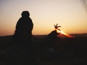 Silhouette woman gesturing ok sign against sky during sunset