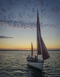 Sailboat sailing on sea against sky during sunset