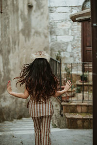 Rear view of woman walking on steps amidst building