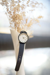 Close-up of wristwatch in flower vase on table