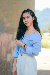 Portrait of beautiful woman standing against wall