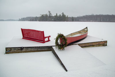 Red canoe and red bench in the snow at christmas