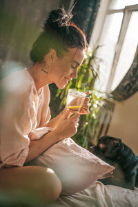 Close-up of woman holding drink sitting outdoors