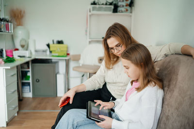 Mom helps daughter teenager with lessons uses tablet for learning