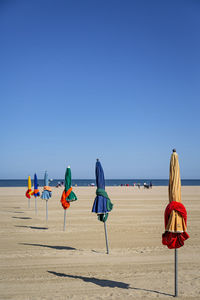 Deck chairs on beach against clear blue sky