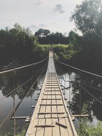 Footbridge over railroad tracks against sky