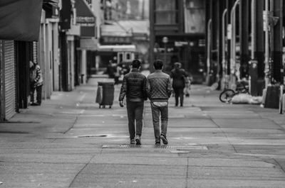 Rear view of people walking on street in city