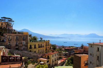 Townscape by sea against clear blue sky