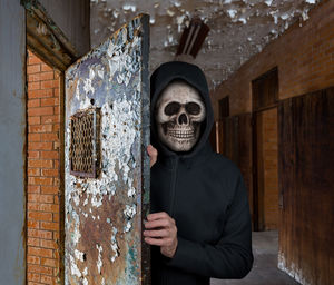 Portrait of person holding mask against wall