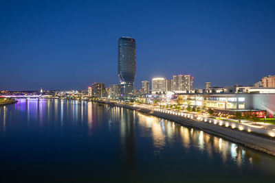 Illuminated bridge over river in city at night