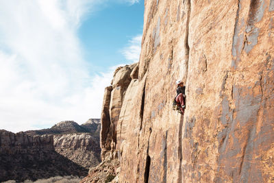 Female hiker climbing mountain against cloudy sky