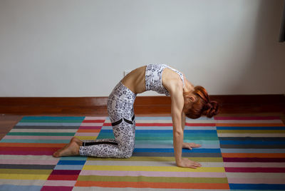 Side view of woman sitting on floor at home