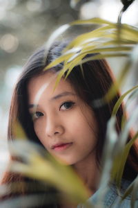 Close-up portrait of beautiful woman seen through plant