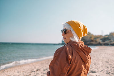 Rear view of woman standing at beach against clear sky