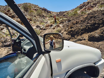 Reflection of woman on side-view mirror of car