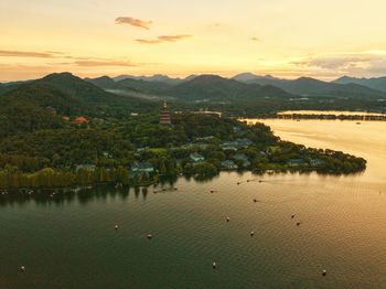 Scenic view of river and mountains against sky at sunset