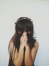 Woman covering face with hair against white background