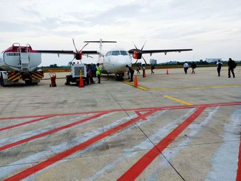 People at airport runway against sky