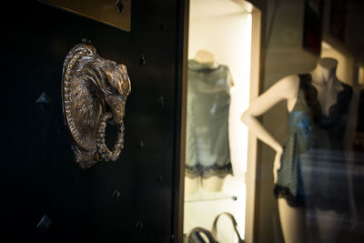 Close-up of bird head door-knocker with a lingerie shop window and silk camisole in the background