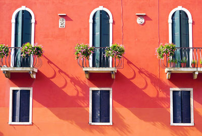 Three doors with terrace and three windows on orange wall building in venice, italy
