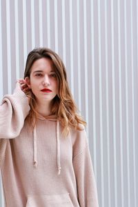 Portrait of beautiful young woman against wall