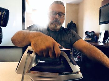 Man ironing while sitting at home