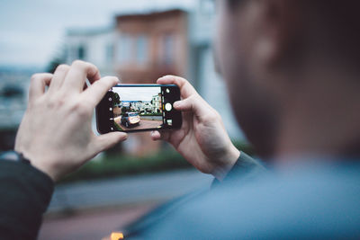 Close-up of man photographing using mobile phone