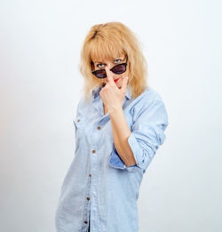 Blonde woman looks at camera through lowered glasses. female curiosity.
