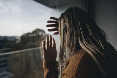 Rear view of woman looking through window