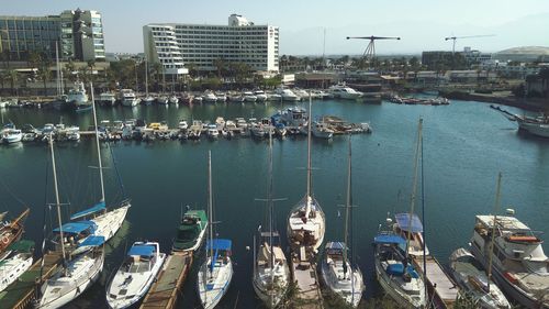 Boats moored at harbor in city against sky